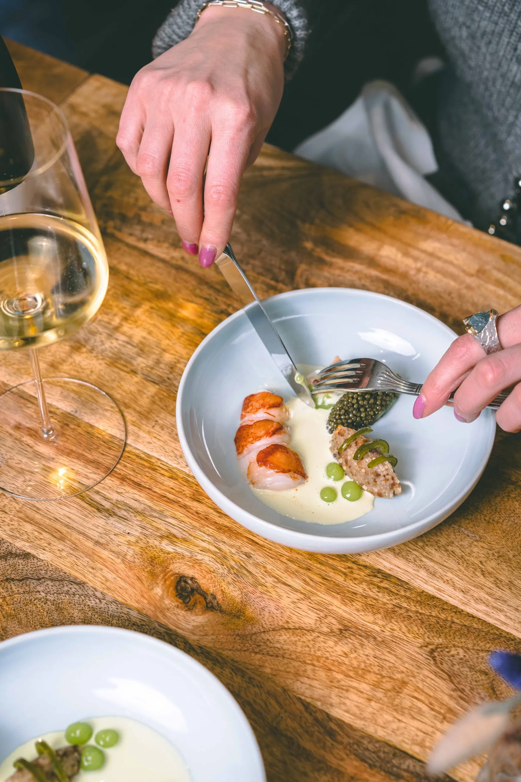 Gäste beim Essen im Bricole, im Vordergrund ein Glas Weißwein