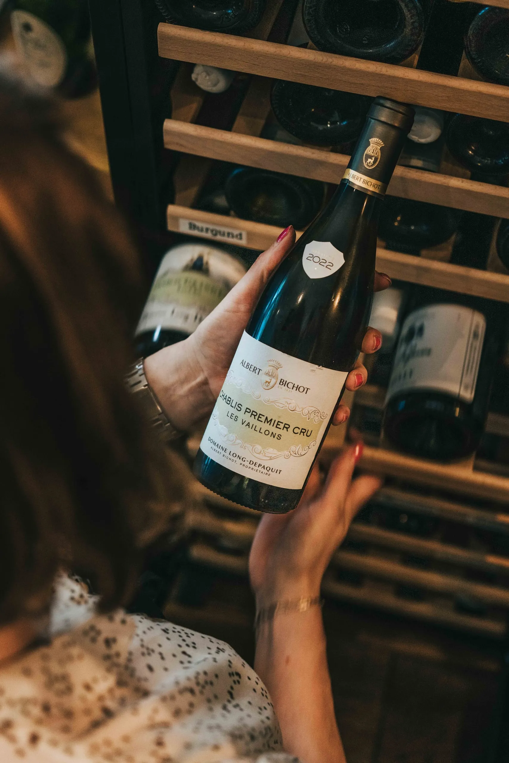 Weinflasche aus dem Bricole-Weinregal in der Hand einer Servicekraft